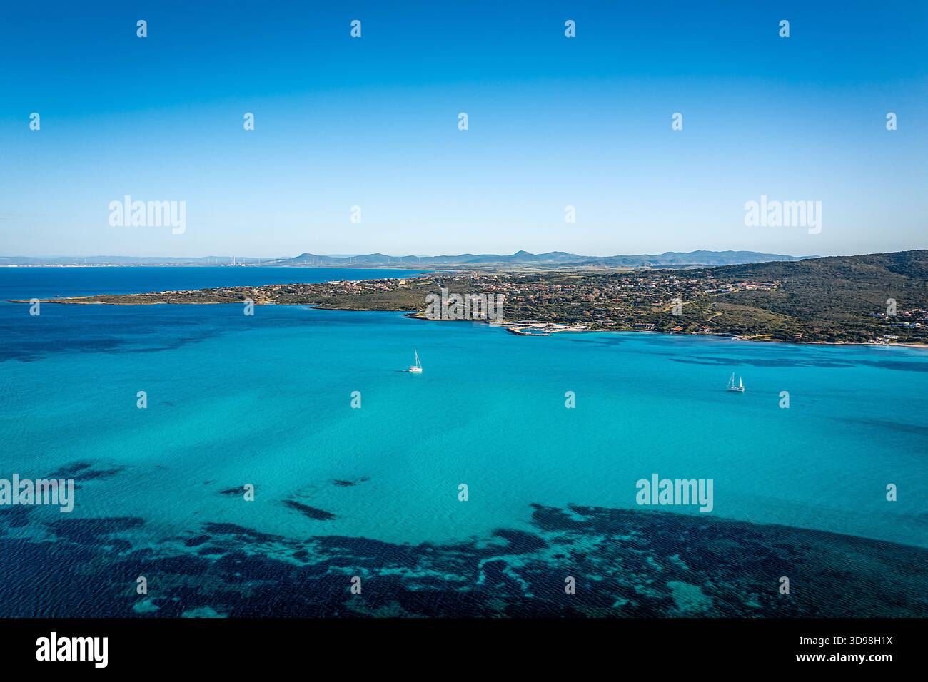 Blick aus der Vogelperspektive auf lebendiges türkisfarbenes Meer, auf eine zerklüftete Küste, kleine Segelboote, die in ruhigen Gewässern treiben, Sardinien, Italien Stockfoto