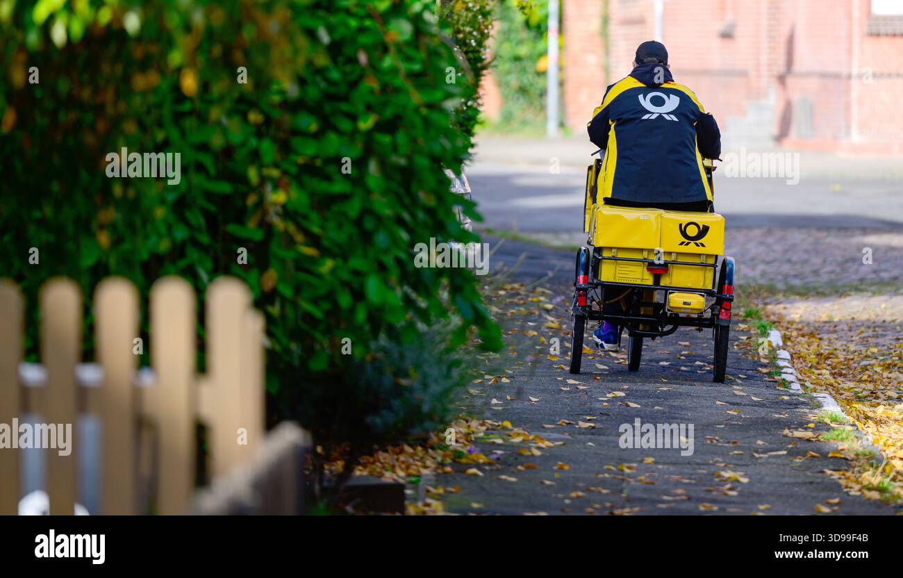 16. Oktober 2025, Niedersachsen, Lüneburg: Eine Briefträgerin fährt auf ihrem Postfahrrad, um Post zuzustellen. Foto: Philipp Schulze/dpa Stockfoto