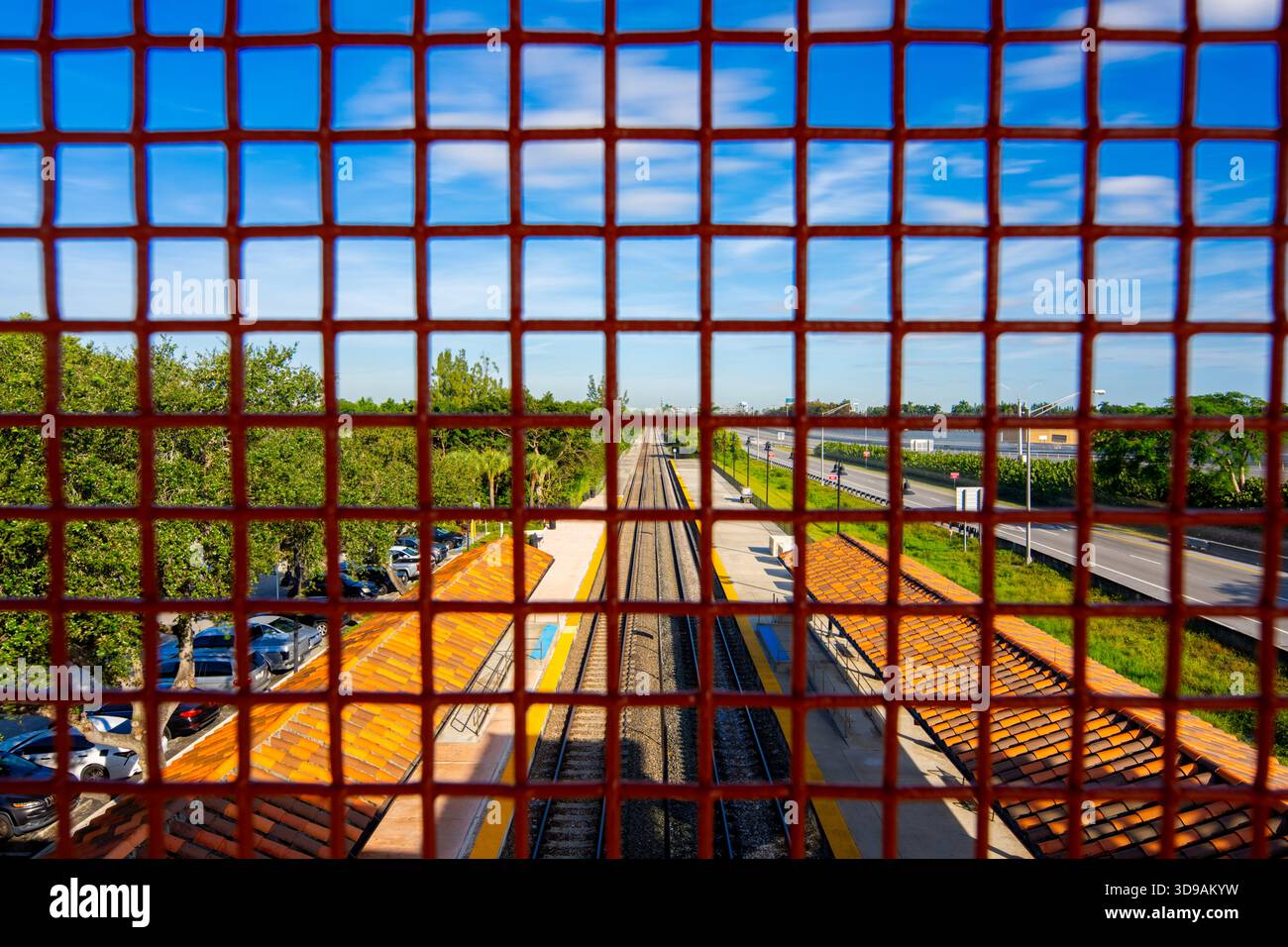 Ich schaue mir Eisenbahngleise durch einen Gitterzaun aus Metall an Stockfoto