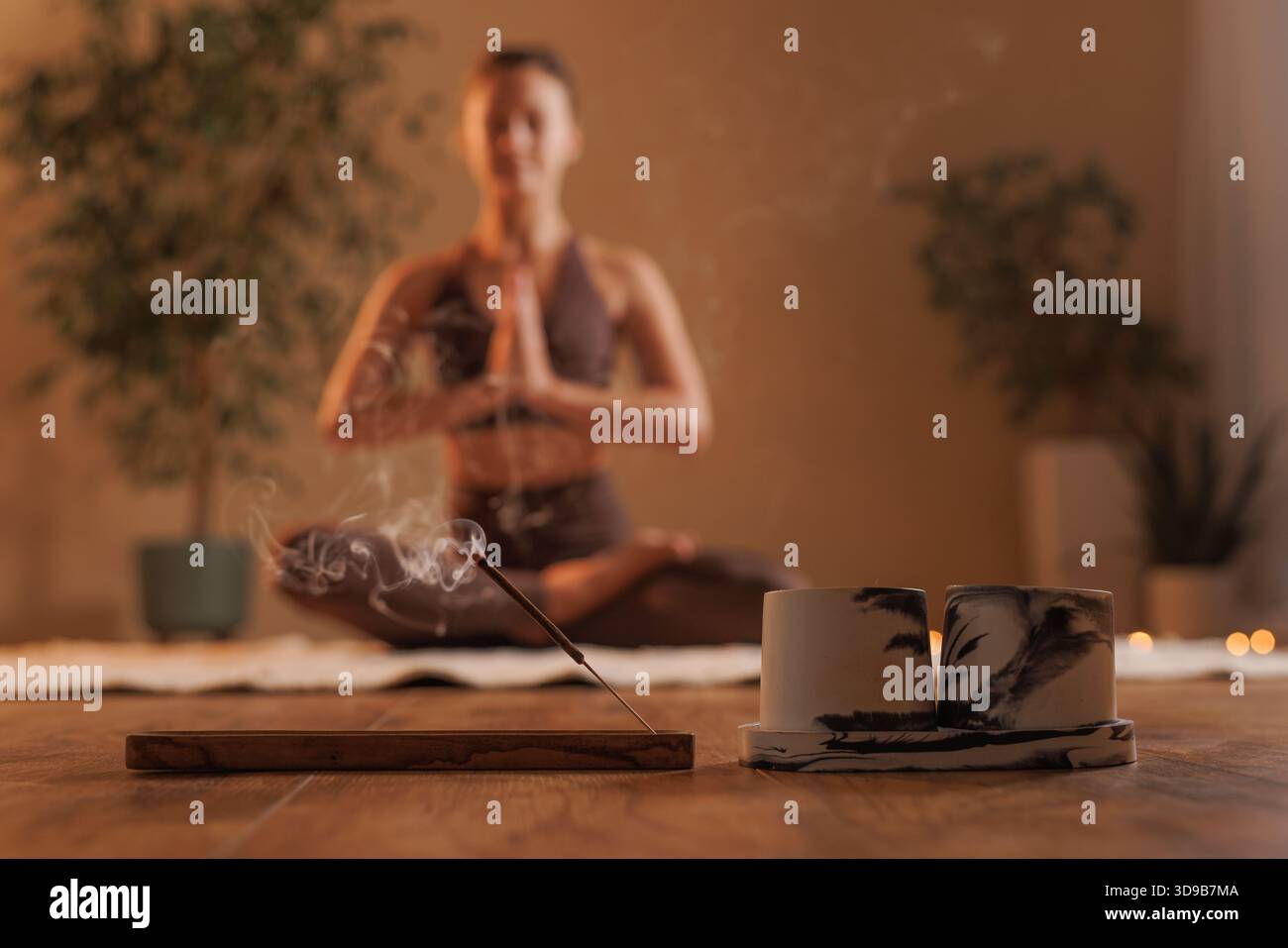 Frau brennender Aromastab für Meditation und Yoga in gemütlicher, warmer Atmosphäre des Raumes, Meditationskonzept Stockfoto