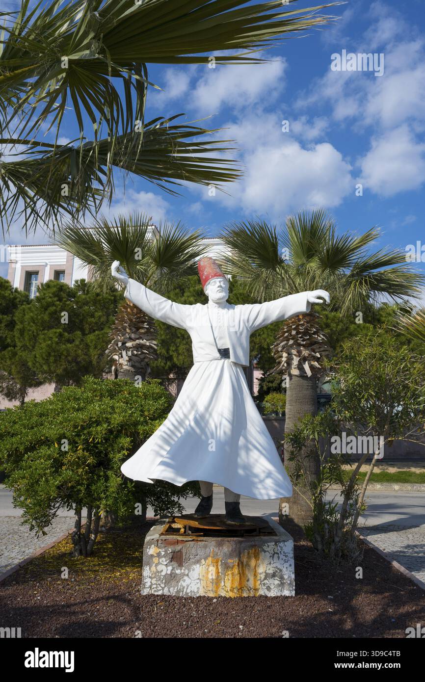 Eine weiße Skulptur eines tanzenden Mannes, umgeben von Palmen unter klarem Himmel, der wirbelnde Derwisch, Alibey Adasi Island, Cunda AdasIJ, Ayvalik Island Stockfoto