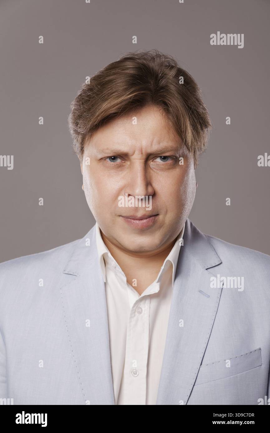 Wütender mittelalter Mann in blauer Jacke, isoliert über grauem Hintergrund Stockfoto