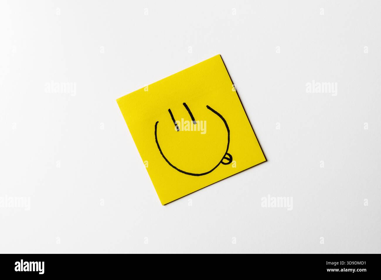 Gelbe Haftnotiz mit einem handgezeichneten Smiley-Symbol auf weißem Hintergrund. Konzeptbild über Glück, positive Stimmung und Emotionen. Stockfoto