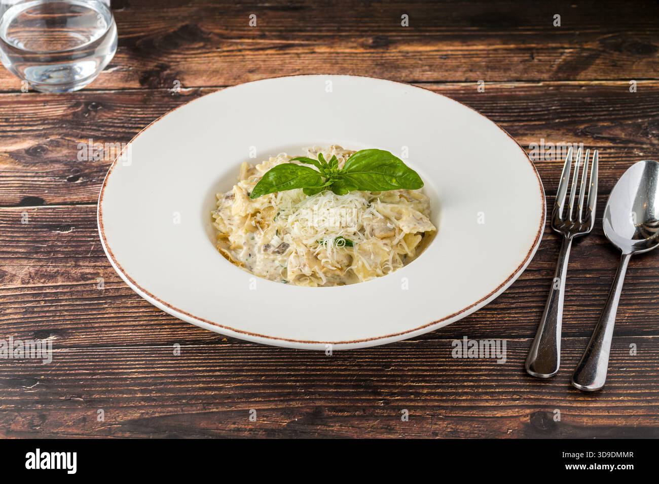 Cremige Pilznudeln mit geriebenem Parmesan und frischem Basilikum Stockfoto
