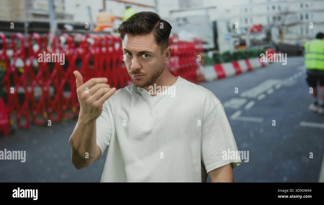 Ein junger Mann mit Bartgesten kommt hier auf der Freiluft-Stadtstraße und zeigt einladenden Ausdruck. Stockfoto