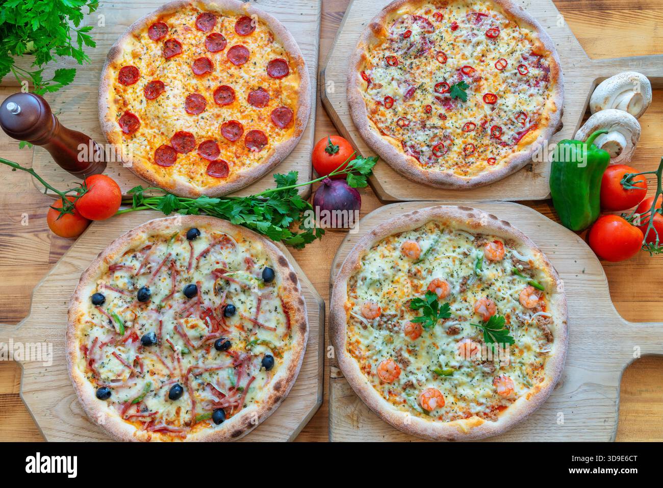 Verschiedene Gourmet-Pizzen mit verschiedenen Belägen auf Holzbrettern, mit lebhaften Farben und frischen Zutaten für kulinarische Genüsse Stockfoto