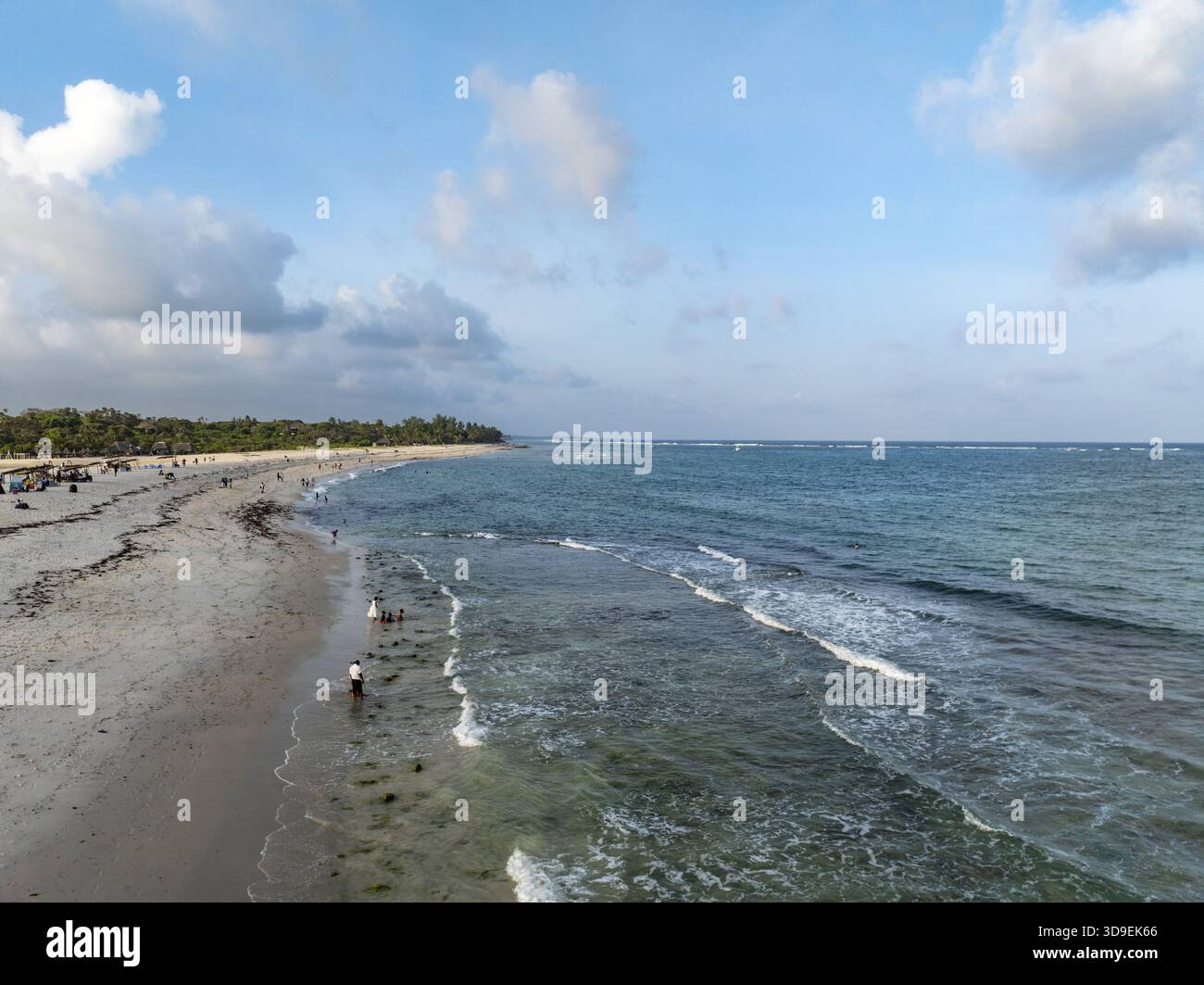 Blick aus der Vogelperspektive auf den Strand, den Sand, der den hellen Himmel reflektiert, und das Wasser, das im Sonnenlicht glitzert, Diani, Kwale County, Kenia. Stockfoto
