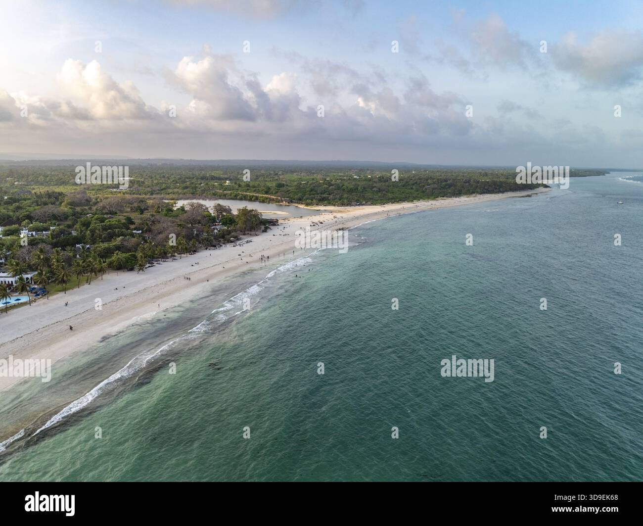Aus der Vogelperspektive auf das türkisfarbene Meer, das die weißen Sandstrände küsst, wo üppige grüne Vegetation auf die Küste trifft, Diani, Kwale County, Kenia. Stockfoto