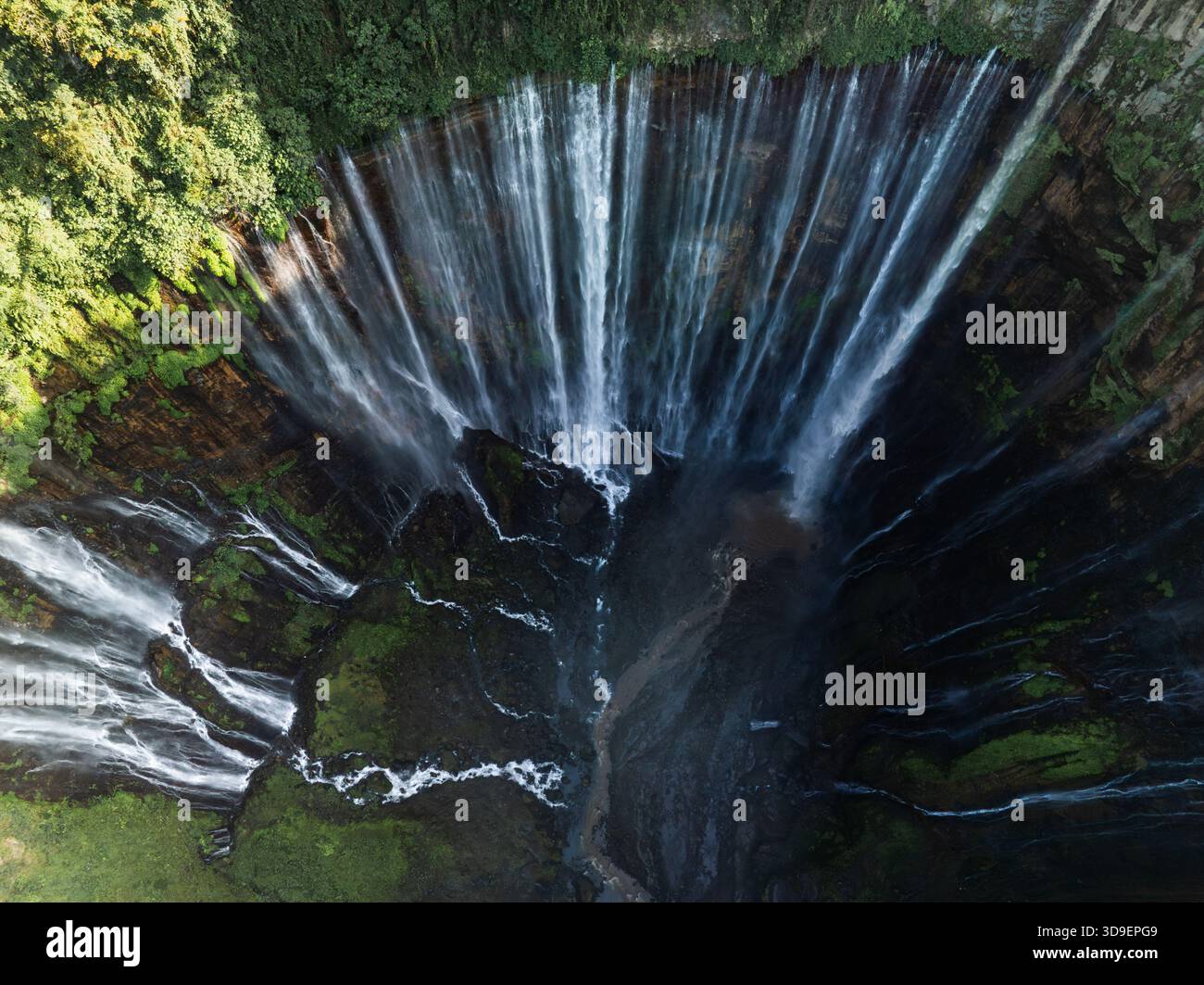 Aus der Vogelperspektive des Tumpak Sewu Wasserfalls stürzt sich dramatisch inmitten der grünen Klippen, Jalan Raya Dampit - Lumajang, Jawa Timur, Indon Stockfoto
