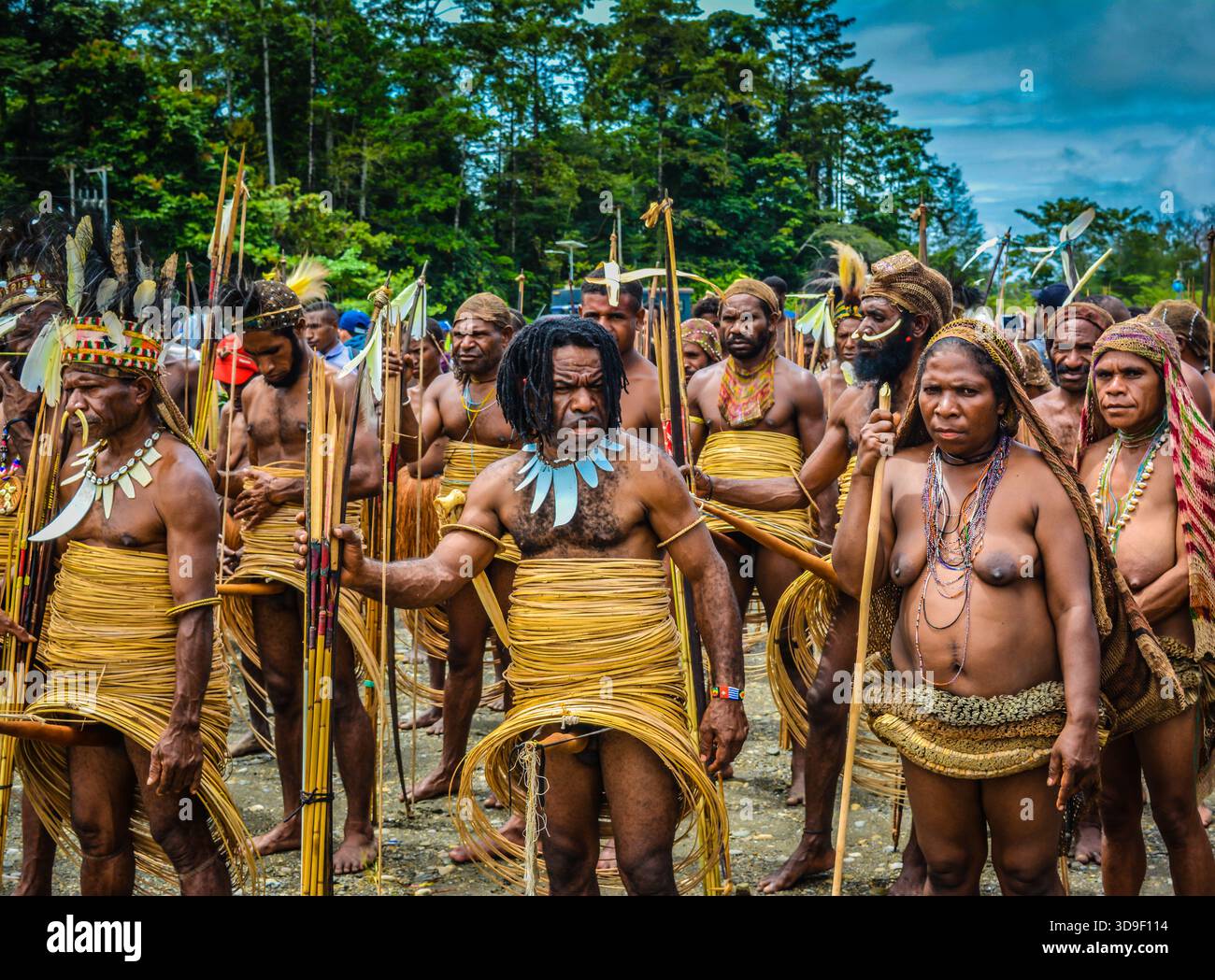 Papuanische Männer und Frauen in traditioneller Stammeskleidung mit Paradiesvögeln und Waffen während einer kulturellen Zeremonie Stockfoto