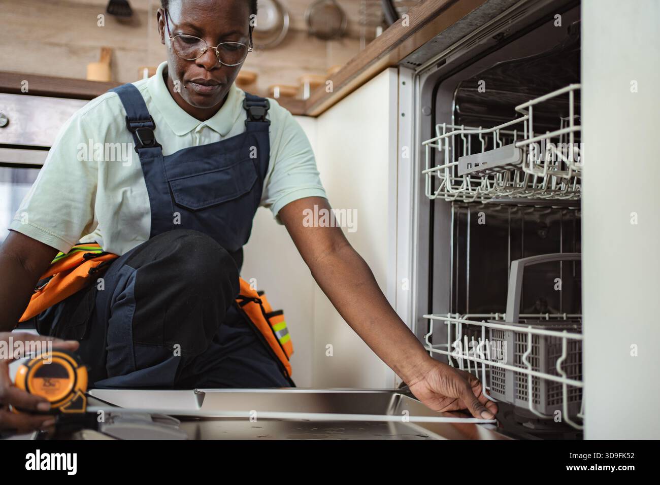 Techniker, der Messungen für die Installation in Geschirrspüler in der Küche durchführt Stockfoto