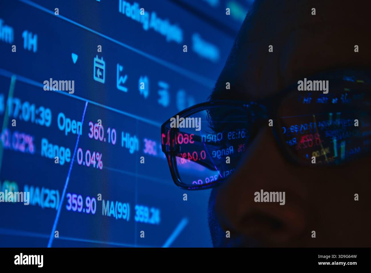 Person, die sich auf Finanzcharts und Handelsdaten von Kryptowährungen konzentriert, auf einem blauen Bildschirm Stockfoto