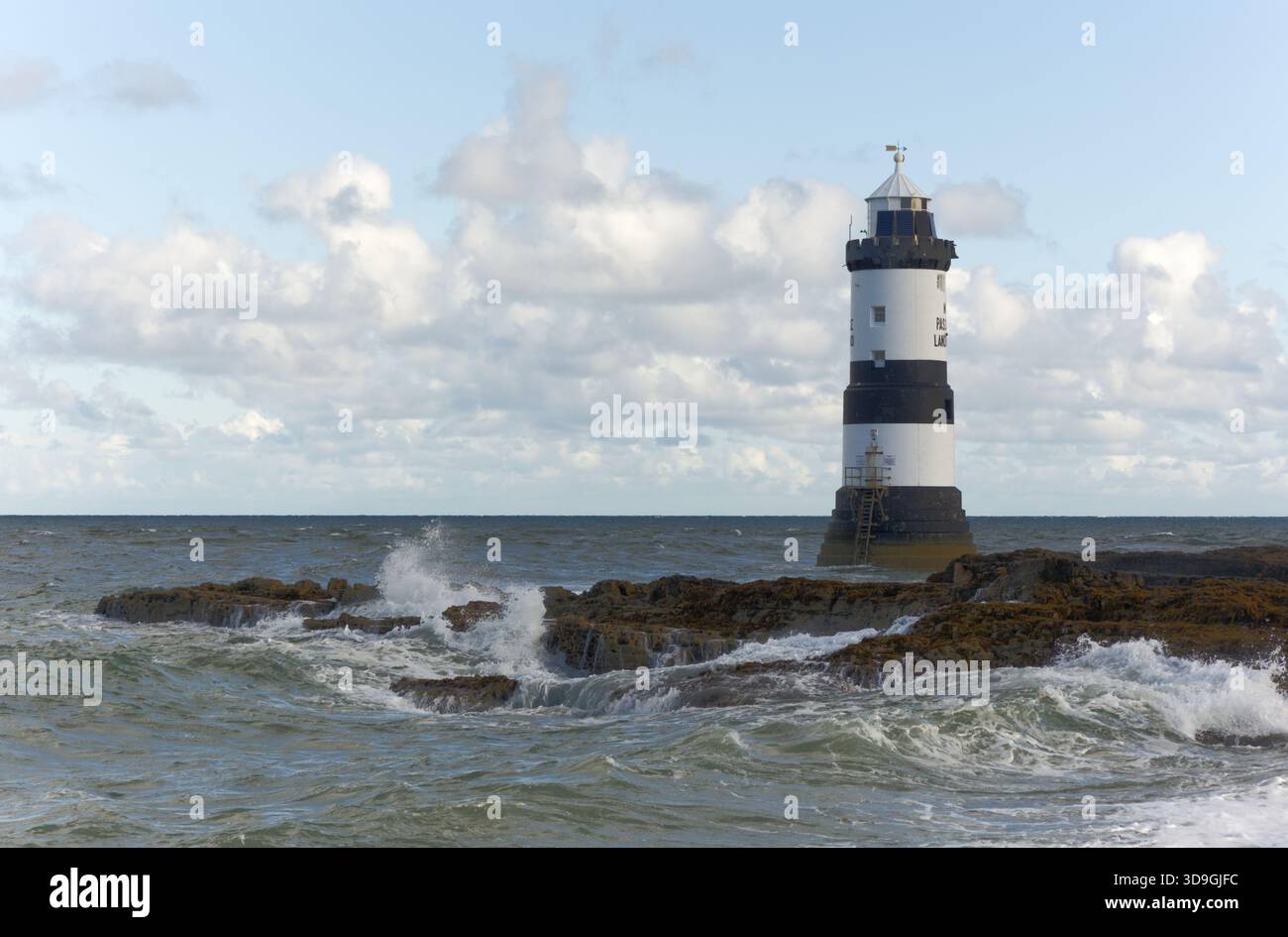 Wellen brechen am Fuße des Trwyn du Lighthouse, auch bekannt als Penmon Lighthouse, am Penmon Point an der Ostküste von an, an der felsigen Küste ab Stockfoto