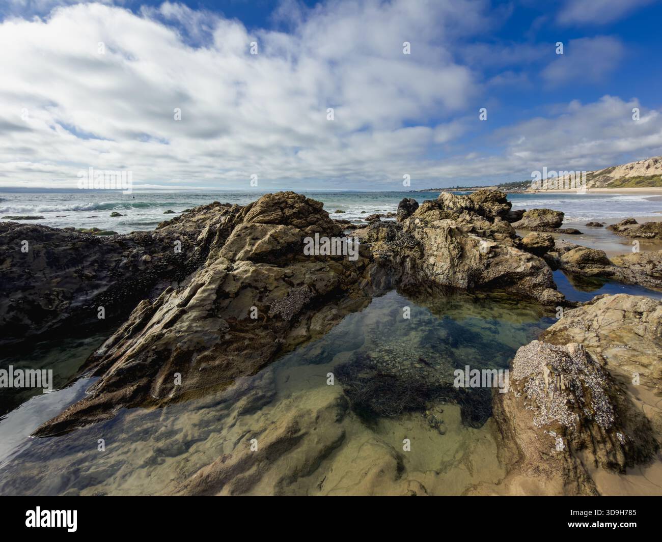 Gezeitenpool am südkalifornischen Strand mit blauem Himmel und weißen Wolken darüber Stockfoto