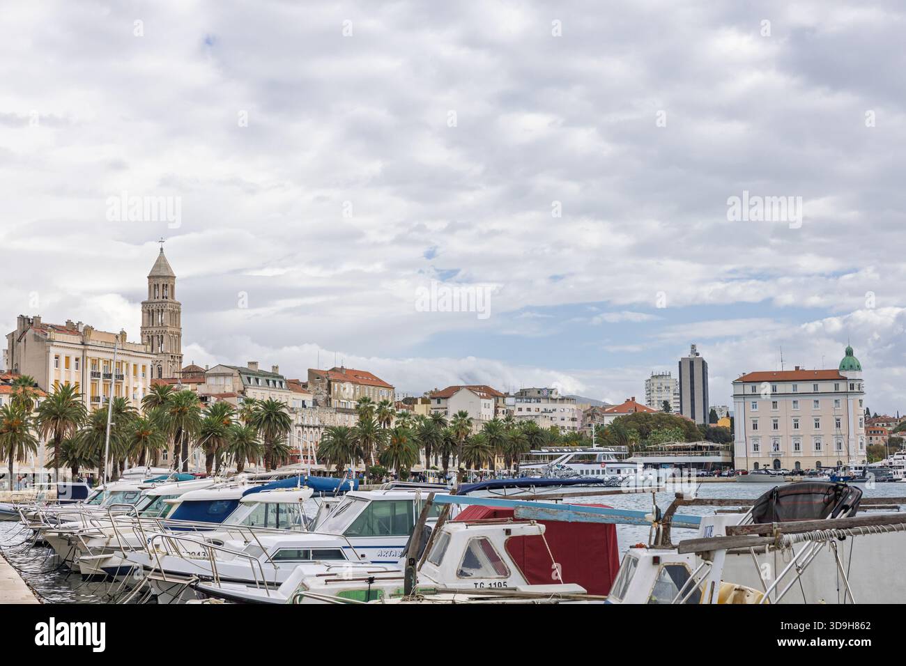 SPLIT, KROATIEN, 10.25.2025: Ein malerischer Hafen gesäumt von Palmen und Booten, umgeben von Steinpromenaden und historischen Gebäuden. Das ruhige Wasser und die Wolke Stockfoto