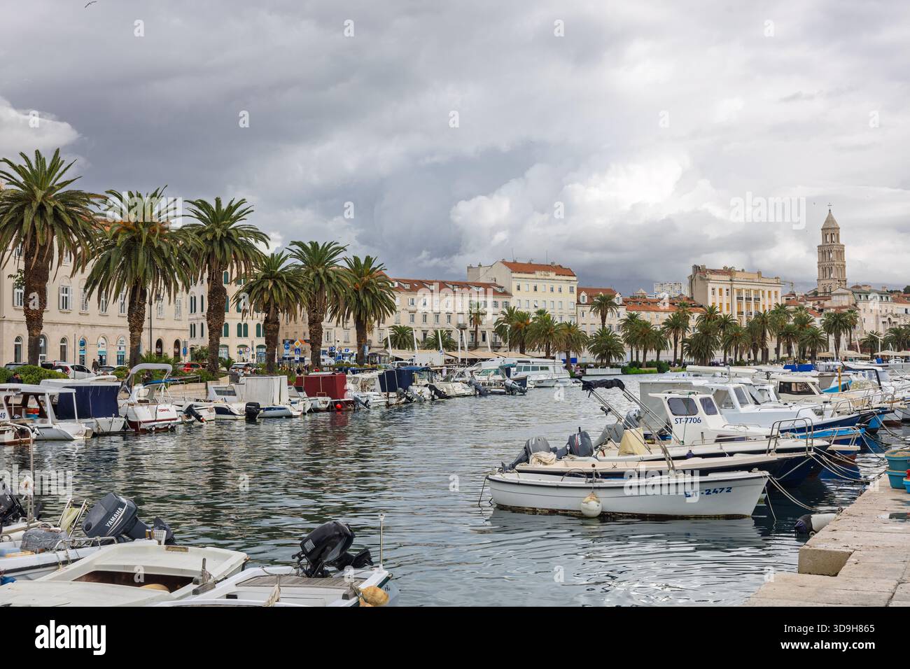 SPLIT, KROATIEN, 10.25.2025: Ein malerischer Hafen gesäumt von Palmen und Booten, umgeben von Steinpromenaden und historischen Gebäuden. Das ruhige Wasser und die Wolke Stockfoto