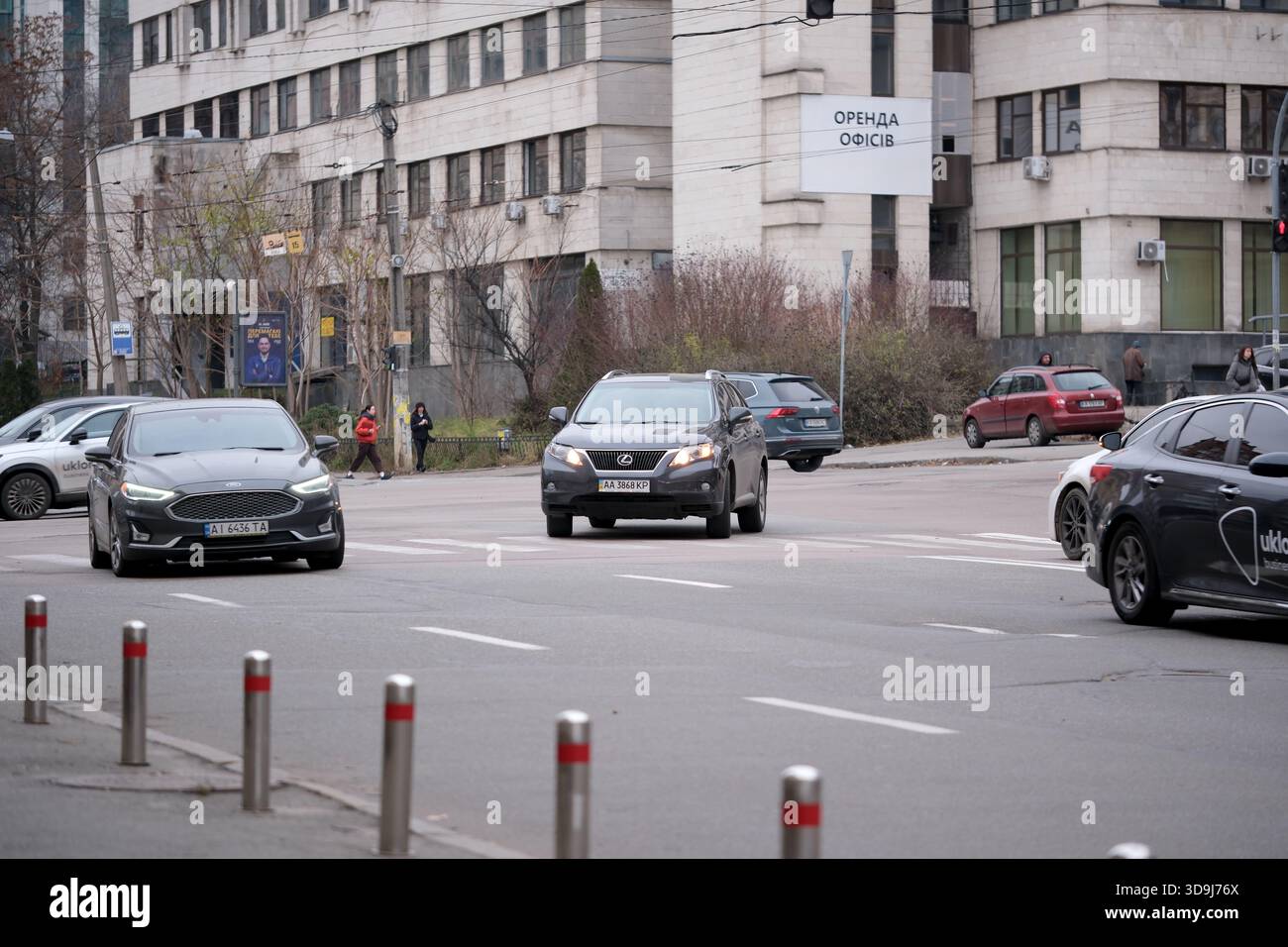 Autos fahren durch eine geschäftige Straßenkreuzung unter grauem Himmel. Kiew, Ukraine. Dezember 2025. Stockfoto