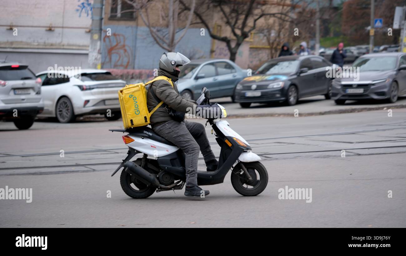 Ein Lieferfahrer manövriert durch den Verkehr auf einer belebten Stadtstraße. Kiew, Ukraine. Dezember 2025. Stockfoto