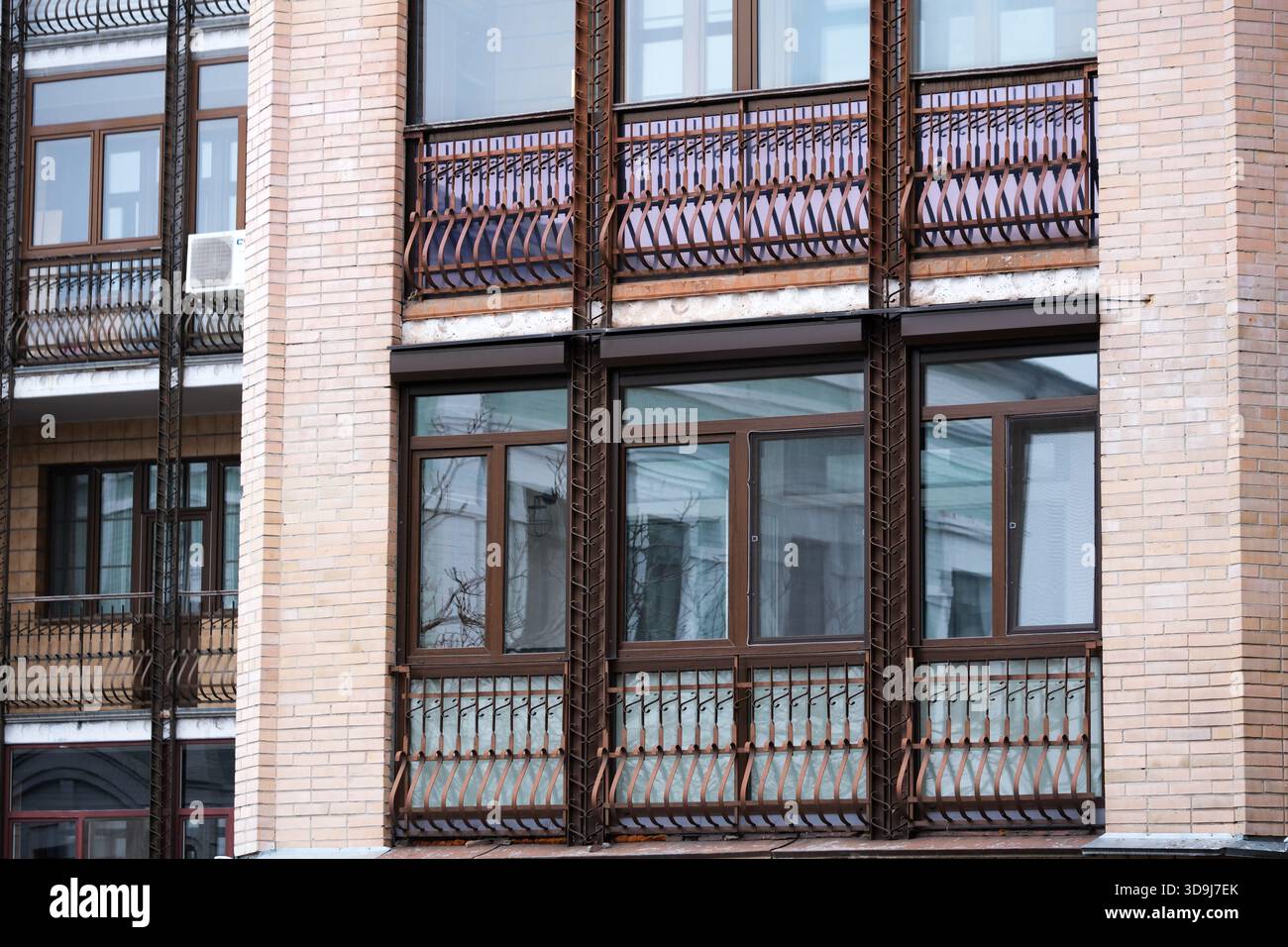Ein stilvoller Balkon mit komplizierten Geländern verleiht der Fassade eines Stadtgebäudes Charme. Kiew, Ukraine. Dezember 2025. Stockfoto