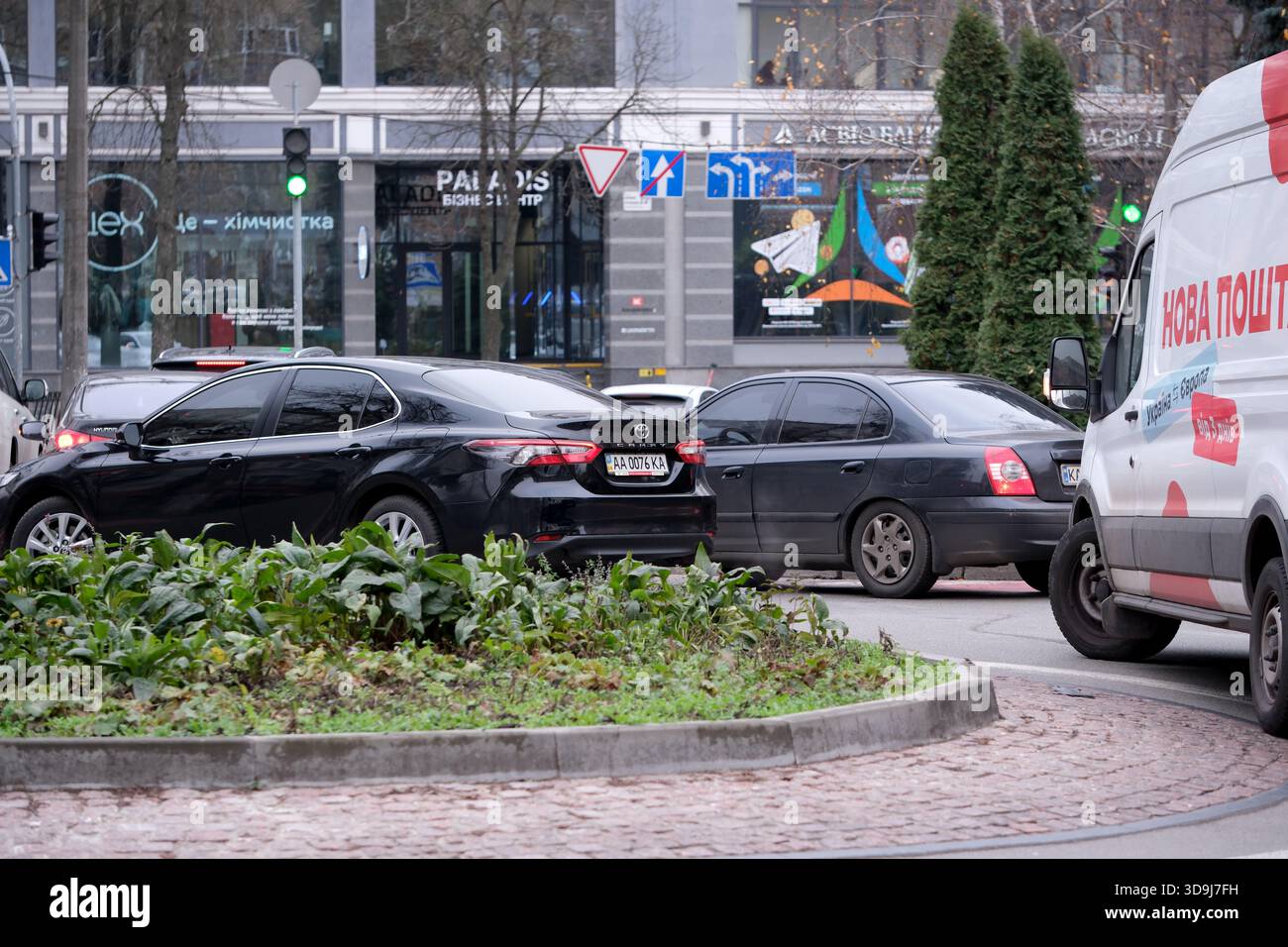 Fahrzeuge manövrieren an einem kühlen Tag in der Stadt durch einen geschäftigen Kreisverkehr. Kiew, Ukraine. Dezember 2025. Stockfoto