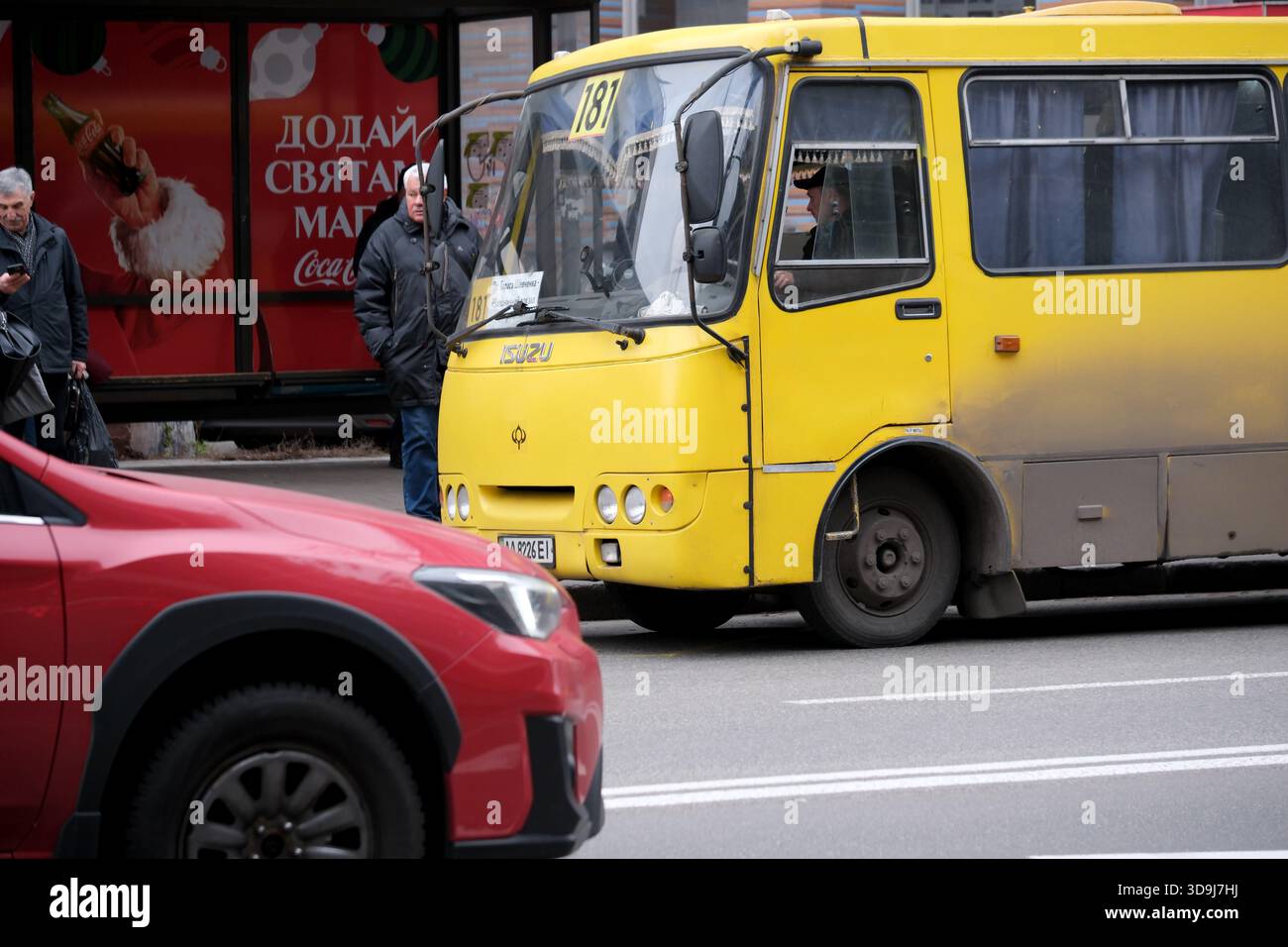 Ein lebhafter gelber Bus fährt tagsüber durch eine geschäftige Stadtszene. Kiew, Ukraine. Dezember 2025. Stockfoto