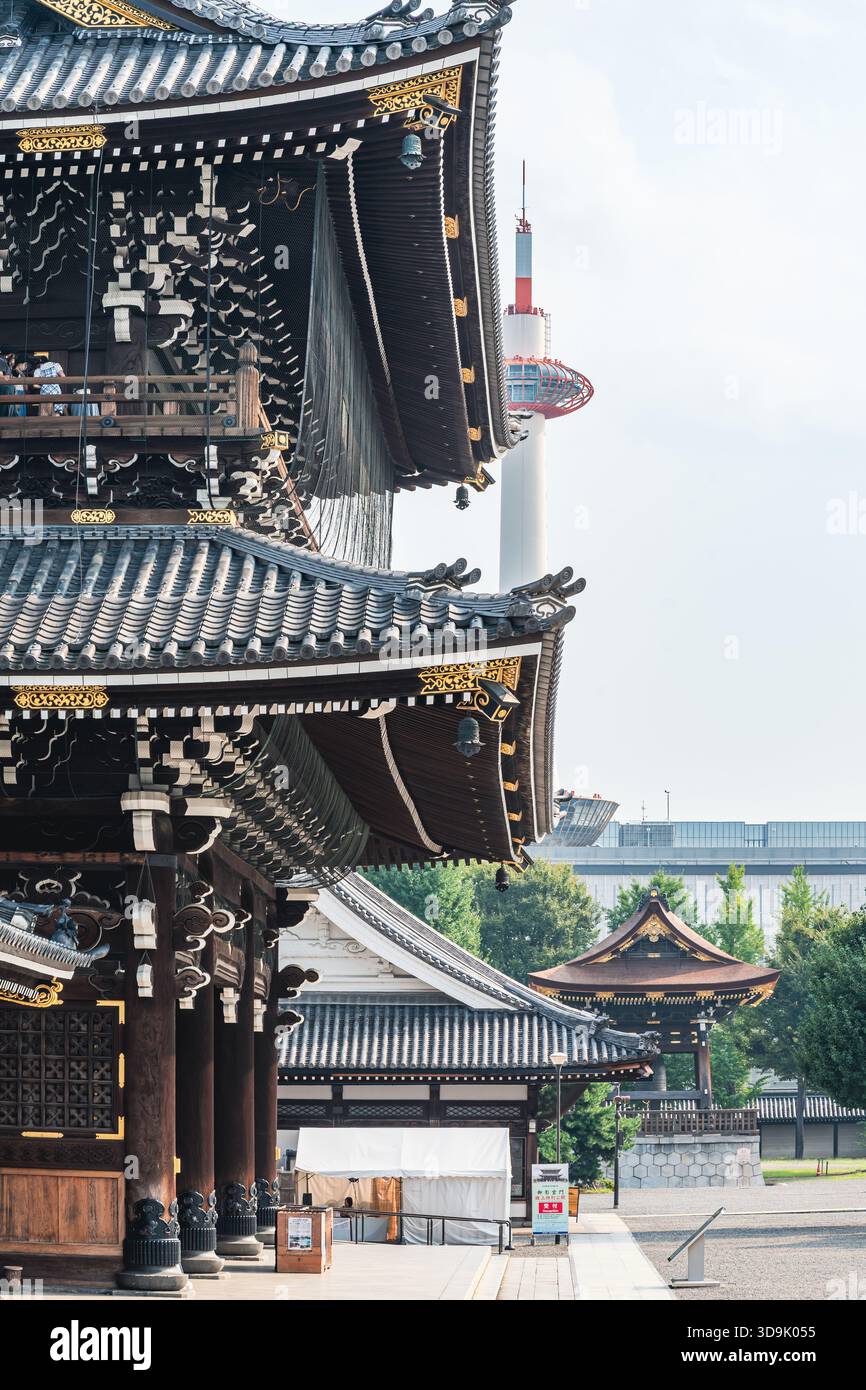 Die klassische japanische Tempelarchitektur mit ihrem mehrstöckigen dunklen Dach und goldenen Akzenten steht in starkem Kontrast zum eleganten, modernen Kyoto Tower in der Nähe. Stockfoto