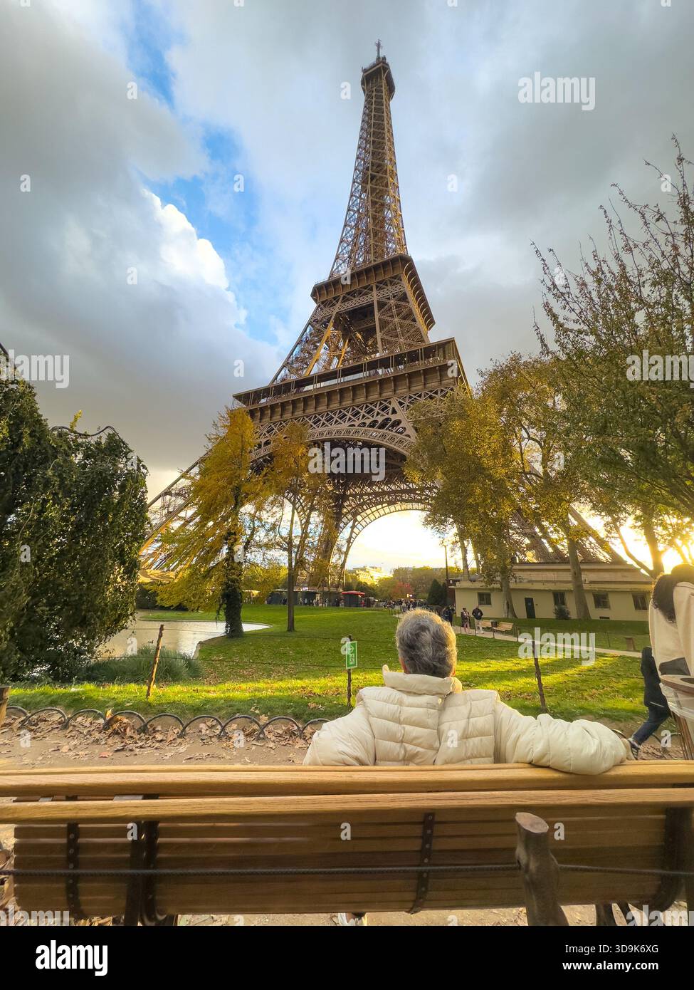 Paris, Frankreich - 25. Oktober 2025: Person, die im Herbst auf einer Parkbank sitzt und den Eiffelturm bestaunt Stockfoto