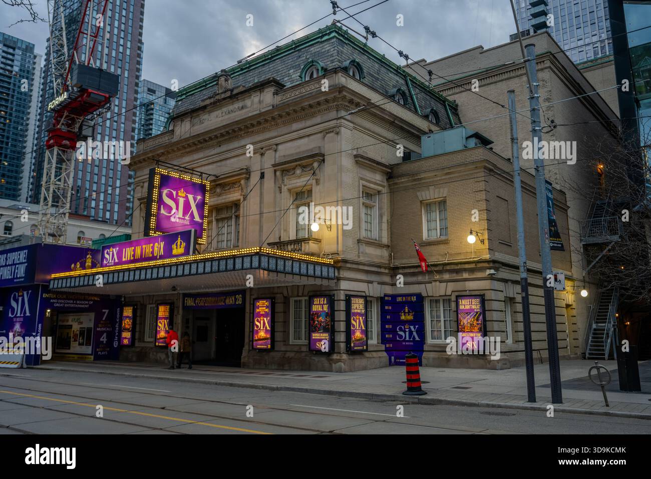 Beleuchtete Plakate für sechs das Musical Licht der Eingang des historischen Royal Alexandra Theatre in Toronto in der Abenddämmerung mit modernen Hochhäusern Stockfoto