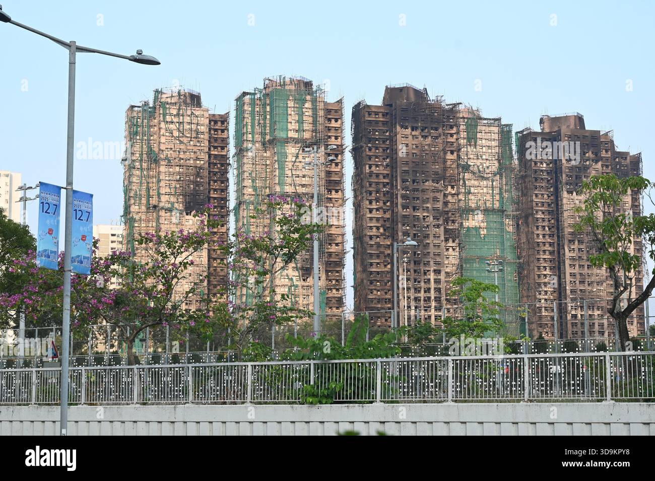 Hongkong, Hongkong. Dezember 2025. Eine Werbung für die Parlamentswahlen des Legislative Council 2025 und den Wohnkomplex des Wang Fuk Court in Tai Po nach einem tödlichen Brand am 6. Dezember 2025 in Hongkong. (Foto: Stringer/Nexpher Images/SIPA USA) Credit: SIPA USA/Alamy Live News Stockfoto