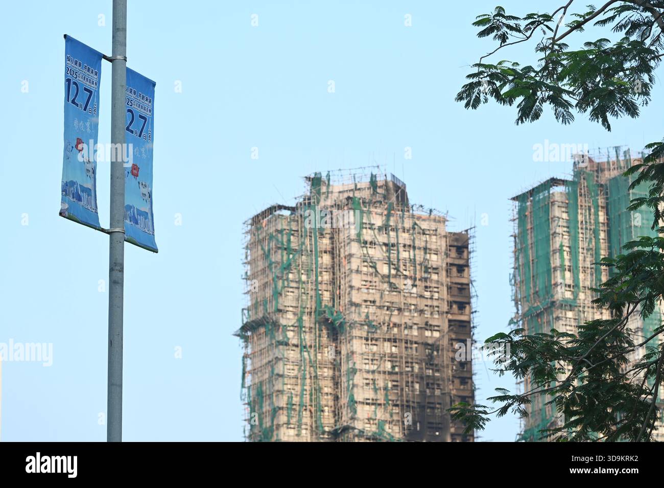 Hongkong, Hongkong. Dezember 2025. Eine Werbung für die Parlamentswahlen des Legislative Council 2025 und den Wohnkomplex des Wang Fuk Court in Tai Po nach einem tödlichen Brand am 6. Dezember 2025 in Hongkong. (Foto: Stringer/Nexpher Images/SIPA USA) Credit: SIPA USA/Alamy Live News Stockfoto