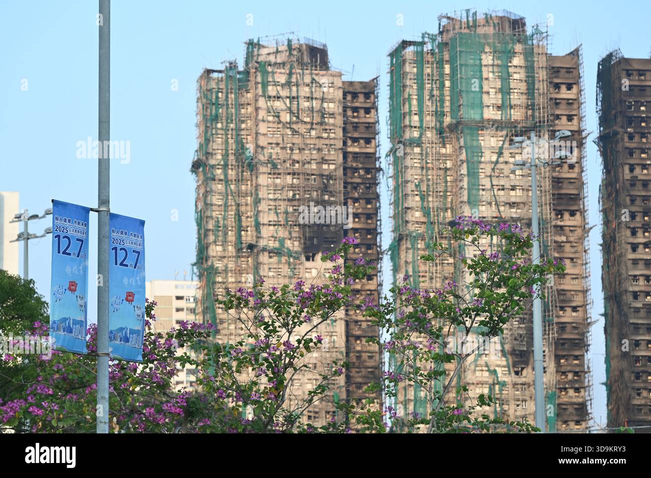 Hongkong, Hongkong. Dezember 2025. Eine Werbung für die Parlamentswahlen des Legislative Council 2025 und den Wohnkomplex des Wang Fuk Court in Tai Po nach einem tödlichen Brand am 6. Dezember 2025 in Hongkong. (Foto: Stringer/Nexpher Images/SIPA USA) Credit: SIPA USA/Alamy Live News Stockfoto