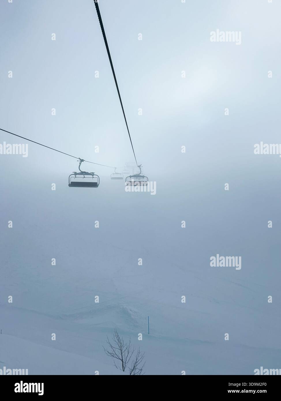 Ein ruhiger Winterblick vom Berg Jahorina mit einem Sessellift, der sich in dicken Nebel erhebt und die Stille und Schönheit eines schneebedeckten alpinen morgens unterstreicht. - Smartphone-aufgenommenes Stockfoto