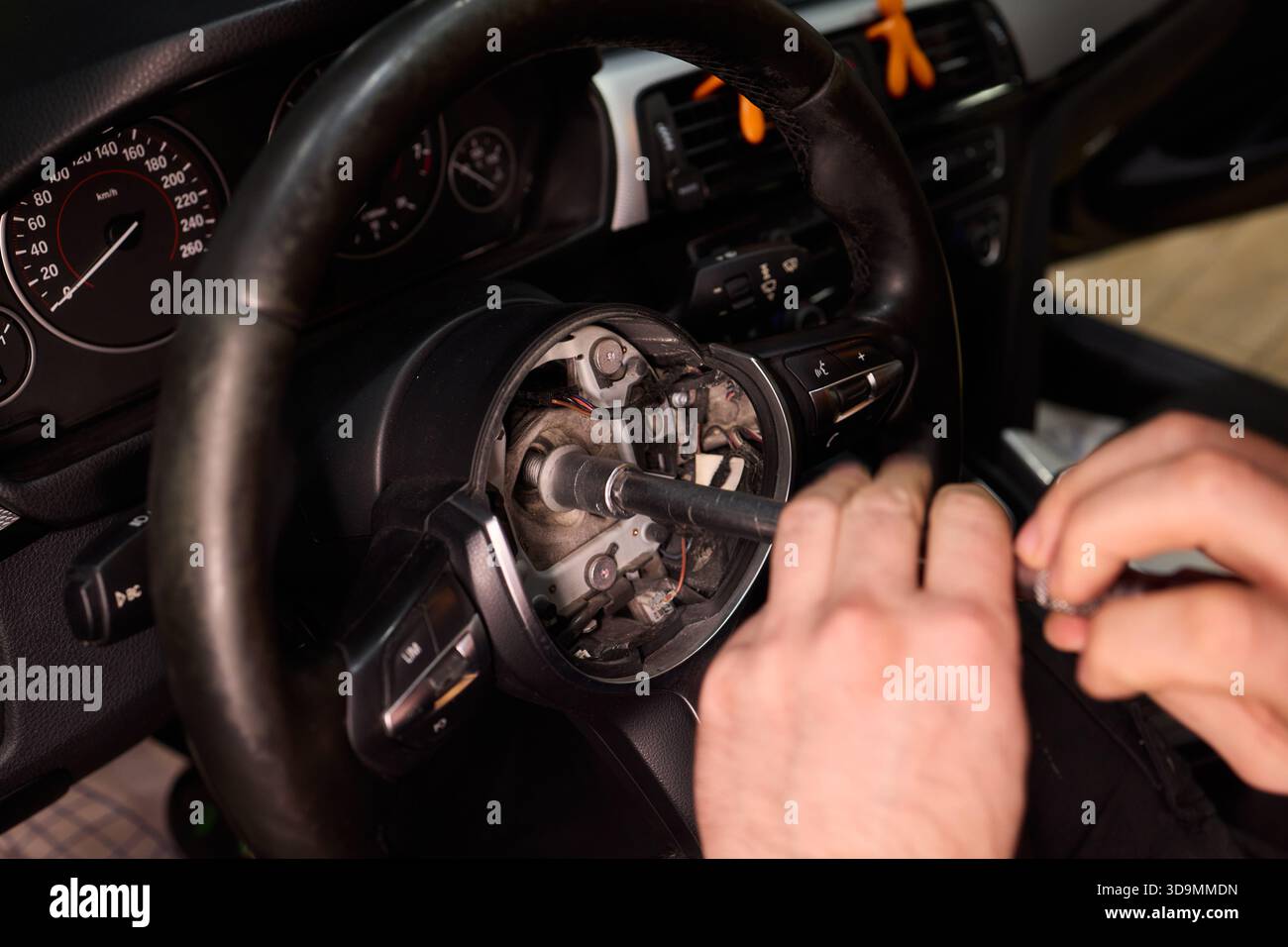 Detaillierte Fahrzeugreparatur, fokussierte Handaufnahme zur sorgfältigen Wiederherstellung des Lenkungsbauteils des Fahrzeugs, Präzisionsarbeiten am Lenkrad des Fahrzeugs mit Werkzeugen in Stockfoto