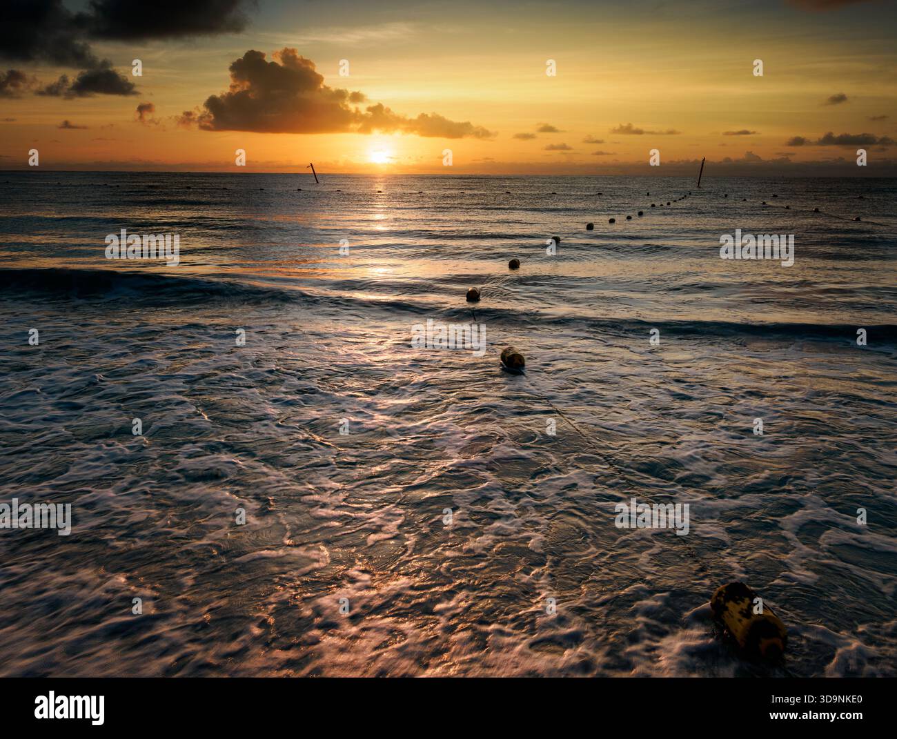 30.12.30 die Bojen eines Haifischnetzes an einem Resort-Strand in Cancun führen über einen ruhigen Ozeanmorgen in den Sonnenaufgang 2024 Stockfoto