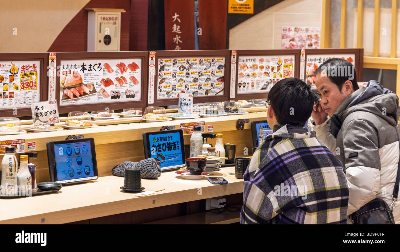 Osaka, Japan - 31. März 2025: Drei Mann hintereinander im Sushi-Restaurant mit Kaiten Beltin Osaka, Japan Stockfoto
