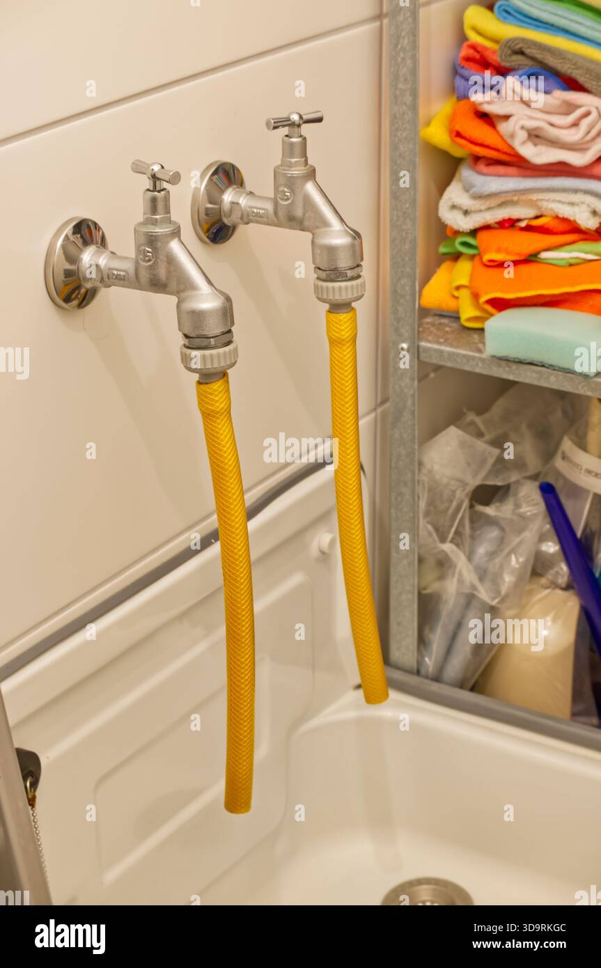 Ein weißer Klinikschrank steht mit offenen Regalen an der Wand. Viele bunte Tücher und Schwämme werden gestapelt und gefaltet für Reinigungsaufgaben, Organizer Stockfoto