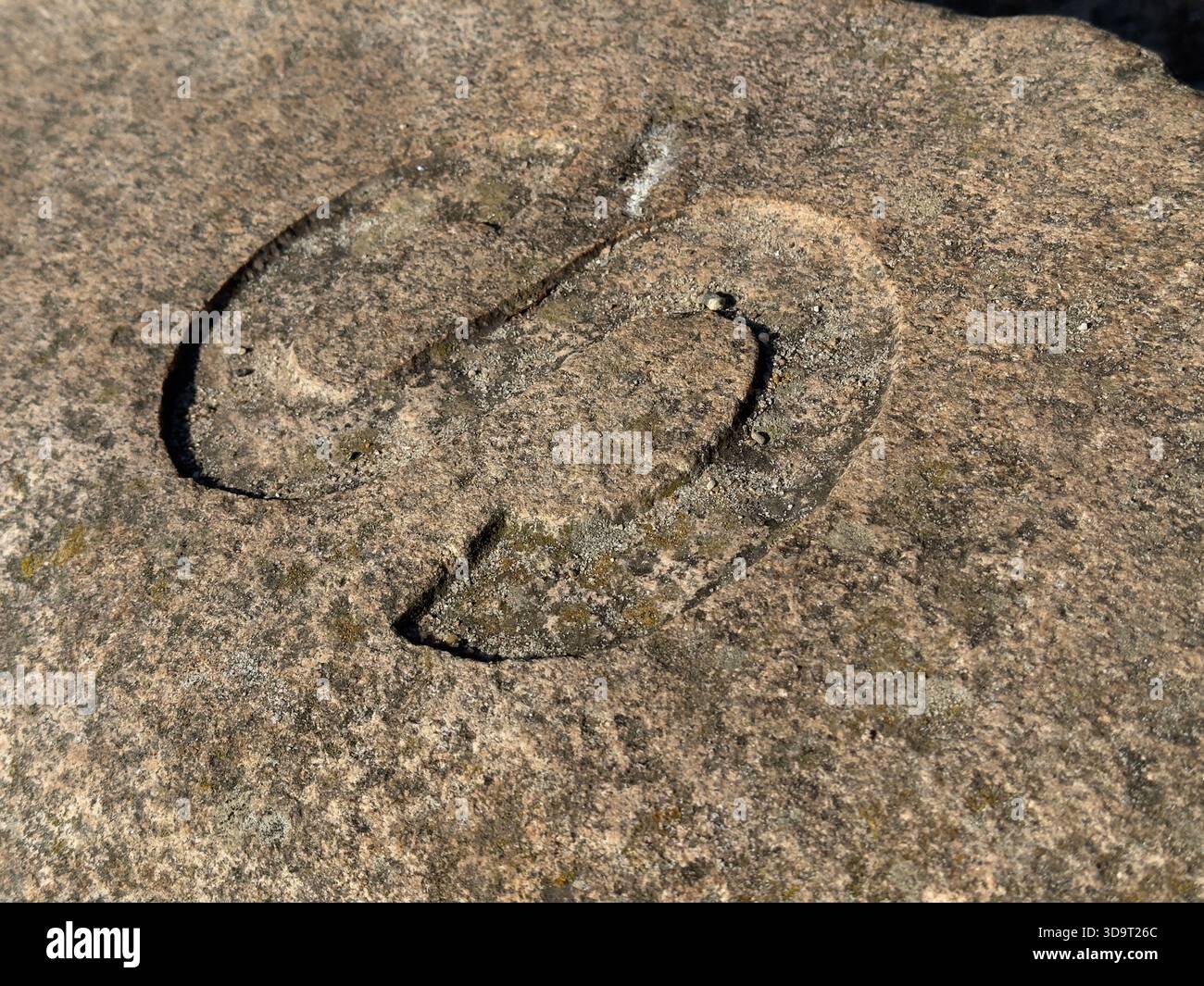 Nahaufnahme eines geschnitzten Symbols auf einer verwitterten Steinoberfläche mit komplexen Details und Texturen. Stockfoto