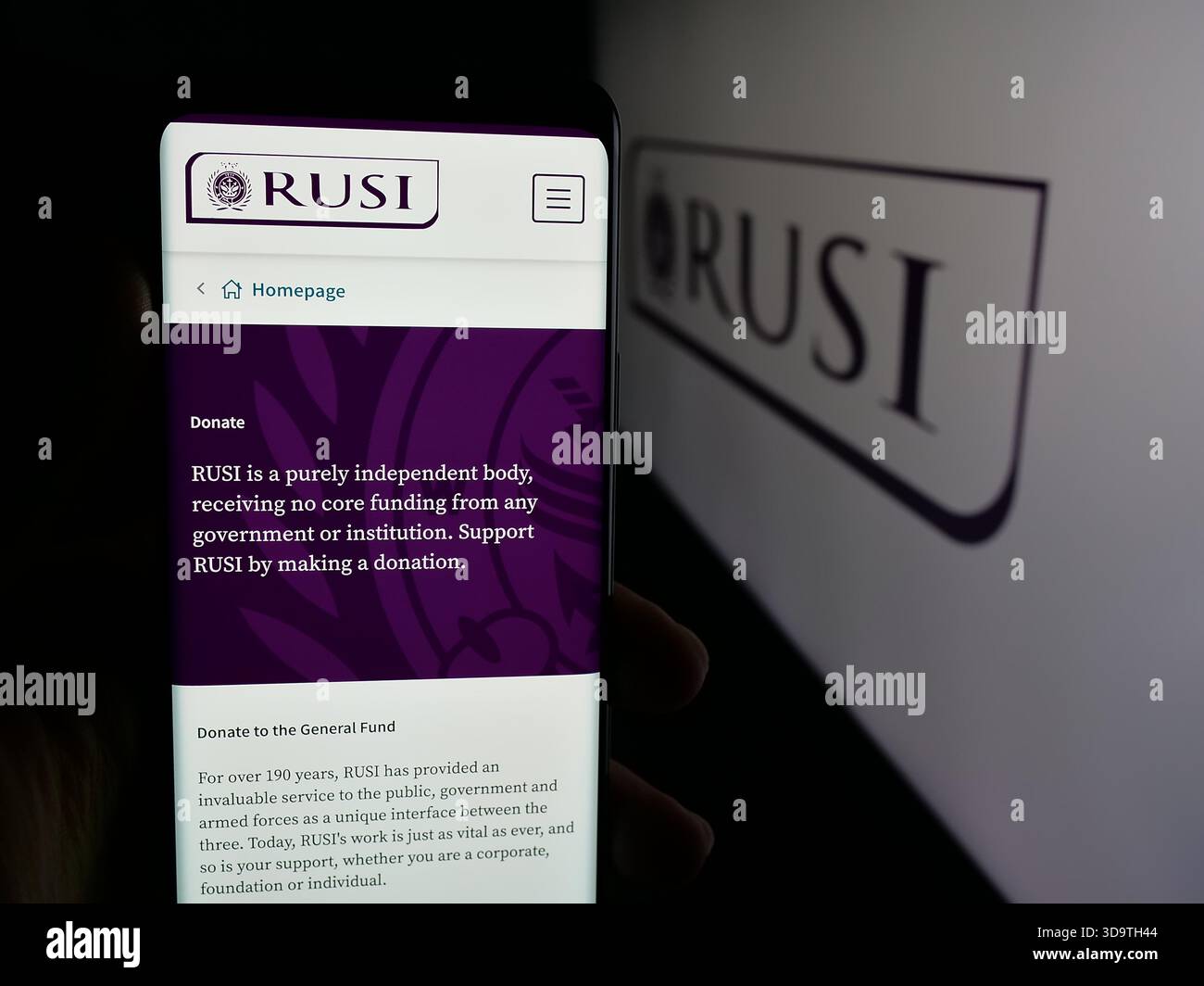 Stuttgart, Deutschland - 24.11.2025: Person, die ein Mobiltelefon hält, mit Webseite des Royal United Services Institute (RUSI) vor dem Logo auf dem Bildschirm. Stockfoto