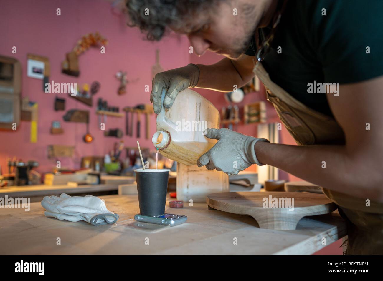 Zimmermann bereitet sich auf die Arbeit vor, misst die benötigte Menge an Epoxidharz auf einer Skala am Tisch. Stockfoto