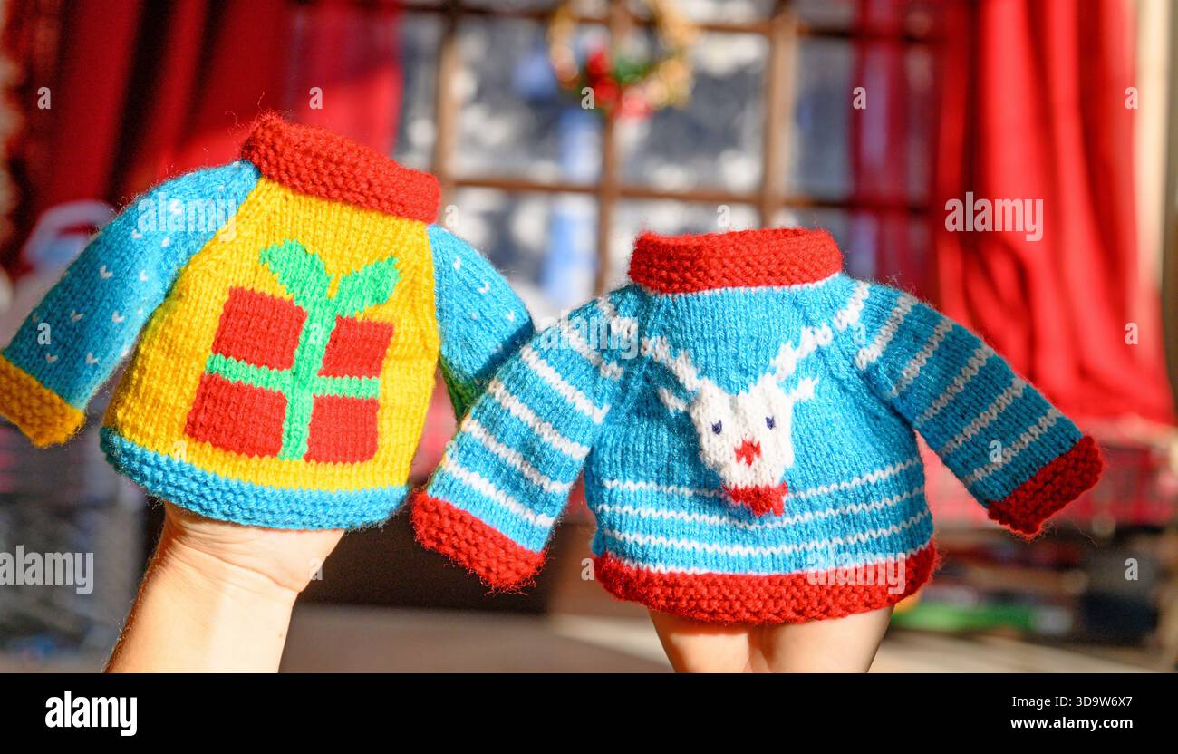Farbenfrohe Miniatur-Strickpullover mit festlichen Mustern wie Schneeflocke, Rentier, Geschenkbox, Weihnachtsbaum und Elfenoutfit Stockfoto