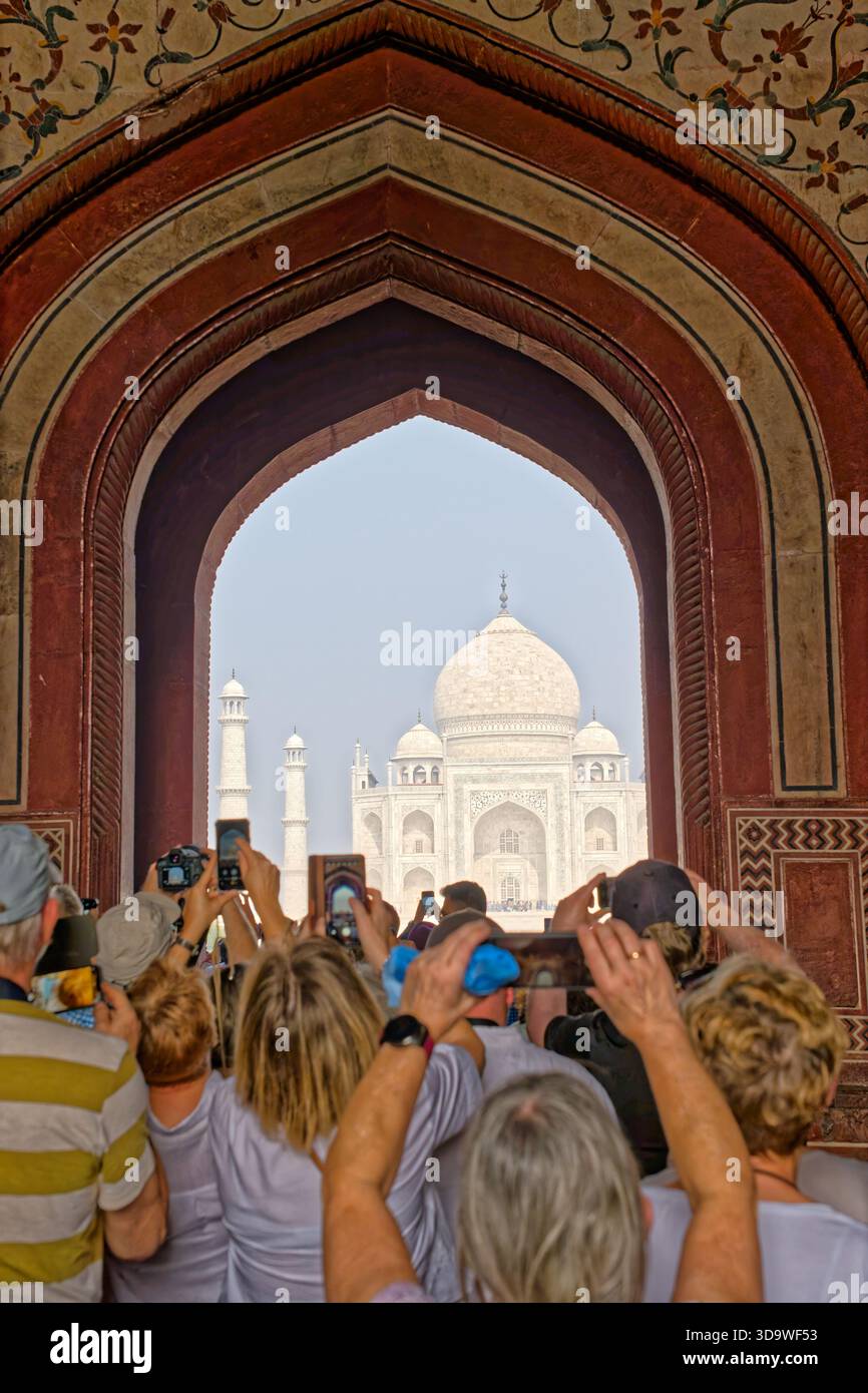 Ein Kuppelturm von Agras Rotem Fort, der zur goldenen Stunde durch einen kunstvollen Bogen gesehen wird, mit einem Vogel, der im warmen Abendlicht auf dem Gipfel thront. Stockfoto