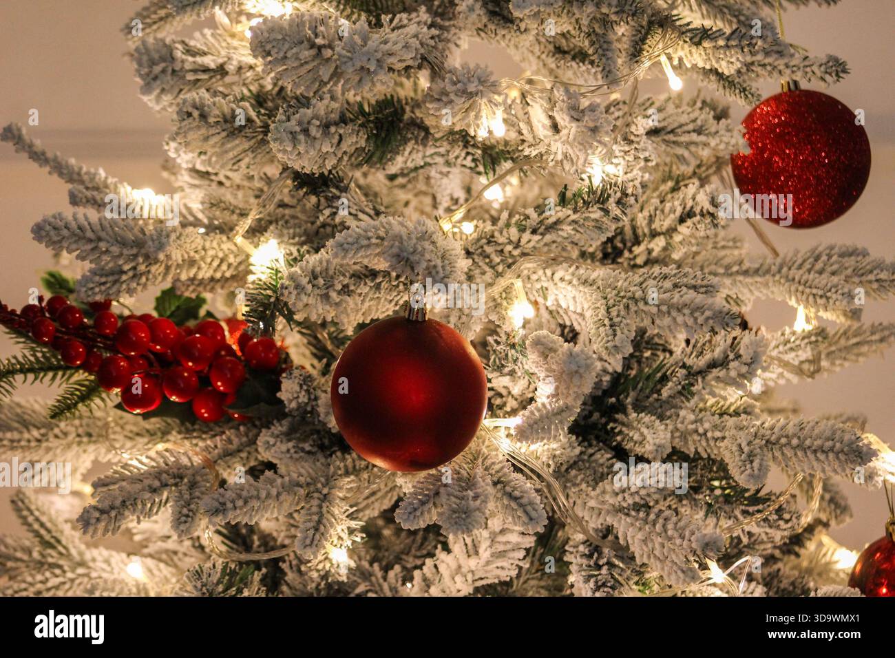 Eleganter Weihnachtsbaum mit roten Ornamenten, Tannenzapfen und verschneiten Zweigen, perfekt für Weihnachtsthemen. Stockfoto