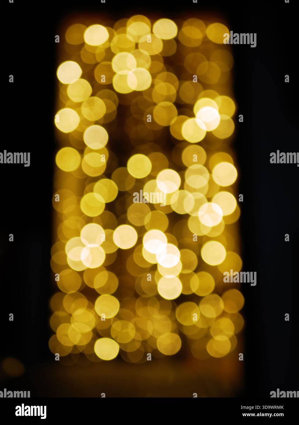Warme goldene Bokeh-Lichter, die sanft vor dunklem Hintergrund leuchten, abstrakte Weihnachtsstimmung, defokussierte Feenlichter-Textur. Pro Foto. Hoch Stockfoto