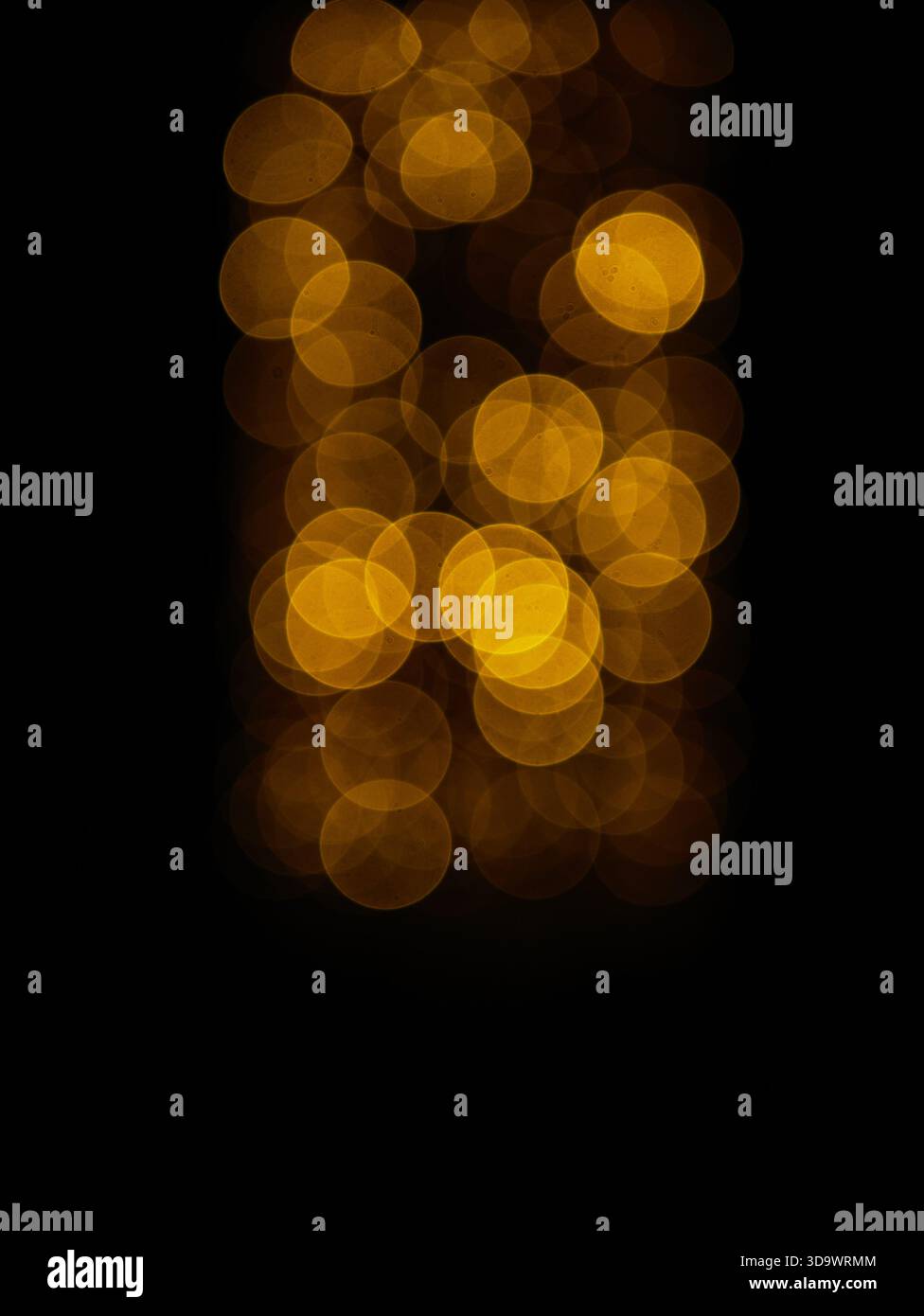 Warme goldene Bokeh-Lichter, die sanft vor dunklem Hintergrund leuchten, abstrakte Weihnachtsstimmung, defokussierte Feenlichter-Textur. Pro Foto. Hoch Stockfoto