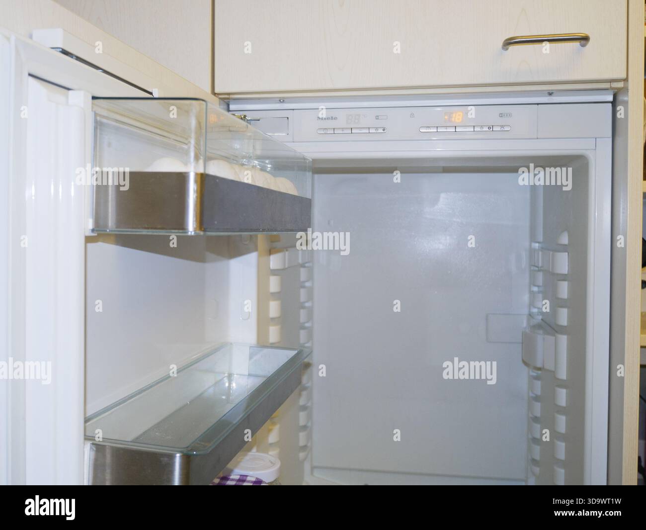 Öffnen Sie den leeren Kühlschrank im Innenraum mit durchsichtigen Einlegeböden und Türfächern, die saubere moderne Küchengeräte für die Aufbewahrung von Lebensmitteln zeigen. Hohe Qualität Stockfoto