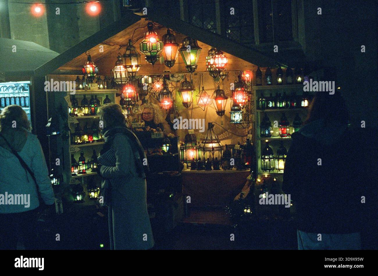 Bath, England - 3. Dezember 2025: Bath Christmas Market, mit Verkaufsständen, Verkaufsständen und Käufern. Aufgenommen nach Einbruch der Dunkelheit auf Spezialfilm. Stockfoto