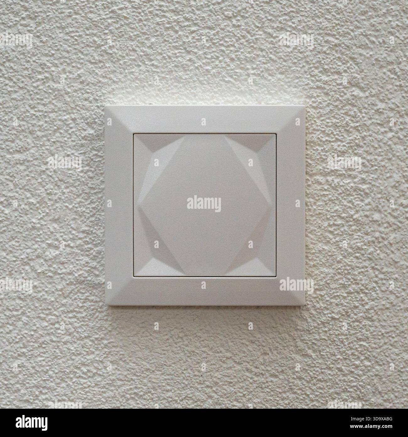 Minimalistische Nahaufnahme eines modernen weißen Wandschalters, der auf einer strukturierten Putzfläche montiert ist. Klare Linien, neutrale Töne und einfaches geometrisches Design Stockfoto