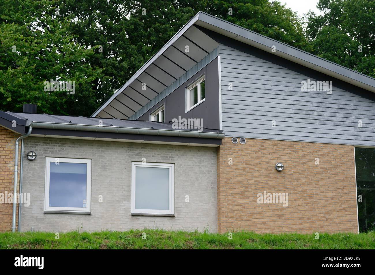 Eine moderne Hausfassade bietet klare Linien, gemischte Materialien und neutrale Farben, die moderne Wohnarchitektur in einem ruhigen Viertel präsentieren Stockfoto