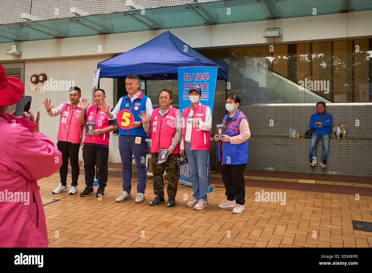 Hongkong, China. Dezember 2025. Ein Kandidat und seine Assistenten werden in der Nähe einer Wahlstation in Tin Shui Wai fotografiert. Die Parlamentswahlen 2025 in Hongkong finden am 7. Dezember 2025 statt, um die 90 Mitglieder des 8. Hongkonger Legislativrates zu wählen. Quelle: SOPA Images Limited/Alamy Live News Stockfoto