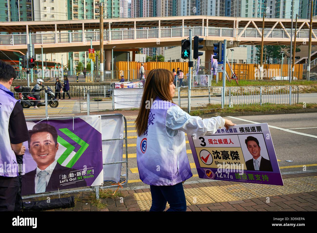 Hongkong, China. Dezember 2025. Der Berater eines Kandidaten zeigt ein Poster seines Kandidaten bei Passanten in der Nähe eines Wahlzentrums in Tin Shui Wai. Die Parlamentswahlen 2025 in Hongkong finden am 7. Dezember 2025 statt, um die 90 Mitglieder des 8. Hongkonger Legislativrates zu wählen. Quelle: SOPA Images Limited/Alamy Live News Stockfoto